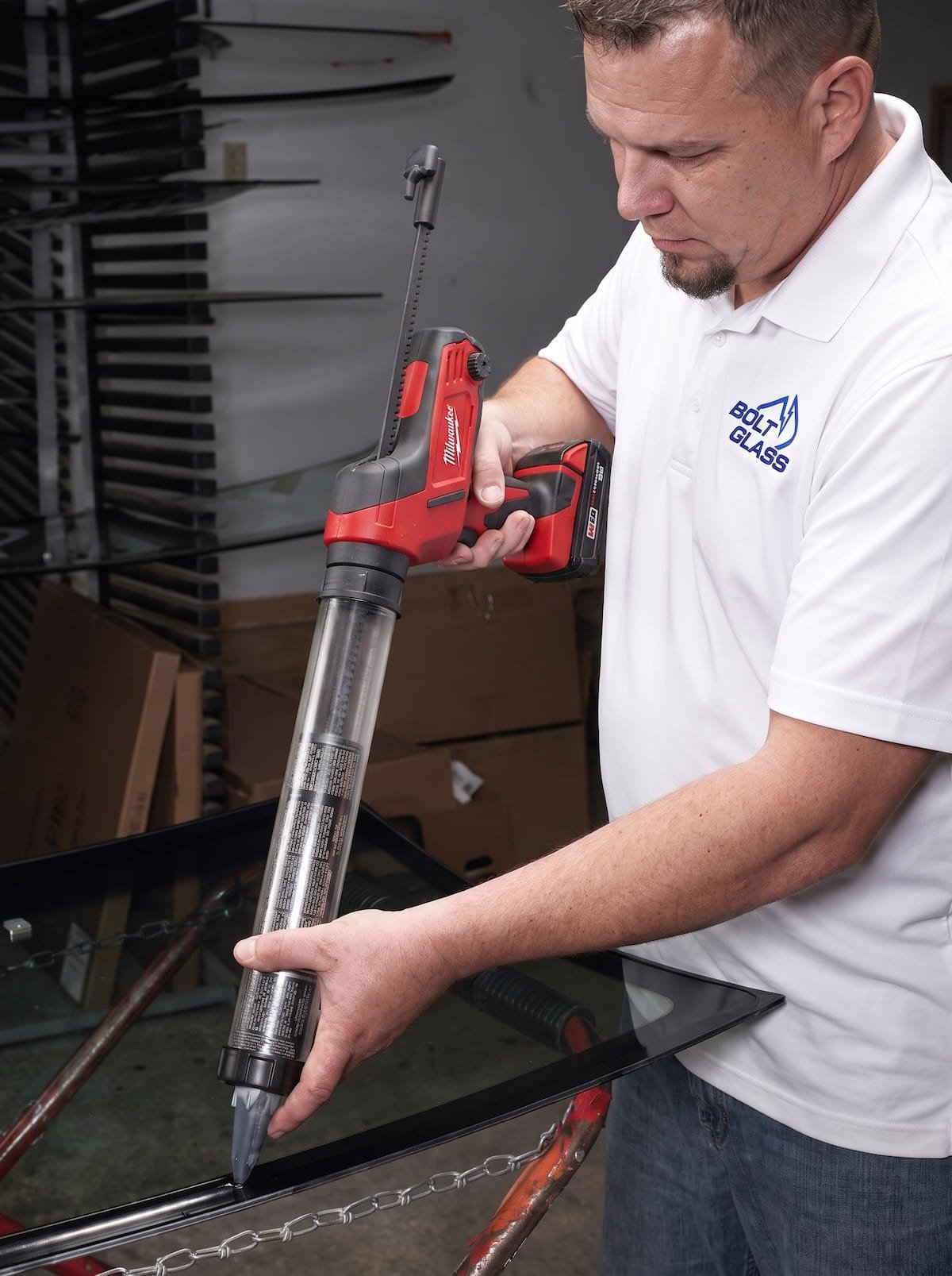 Technicien Bolt Glass appliquant la colle avant pose du pare-brise